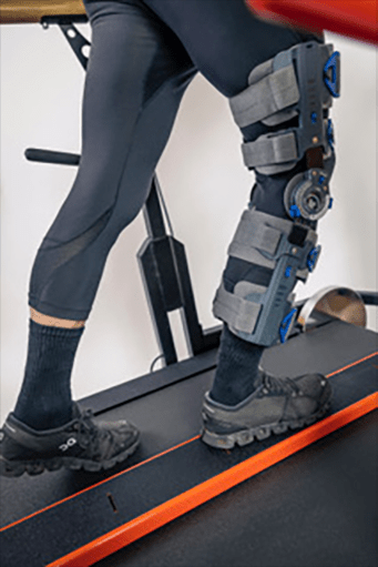 Bein mit Knieorthese trainiert auf dem ScootTrain Gangtrainer in der Reha